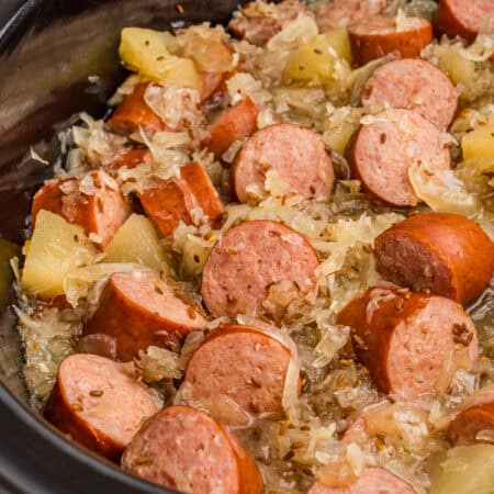 Kielbasa with sauerkraut, caraway seeds, and apple chunks in a crock pot.