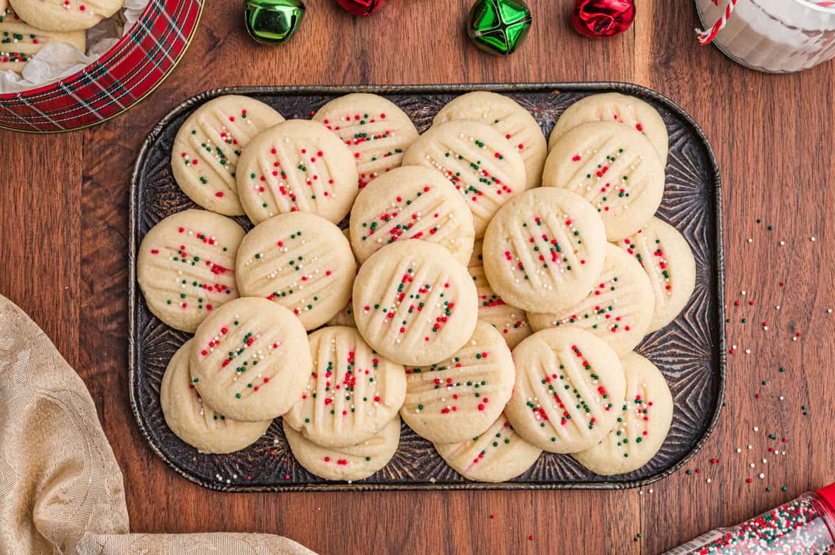 Whipped shortbread cookies with red. and green sprinkles on a tray.