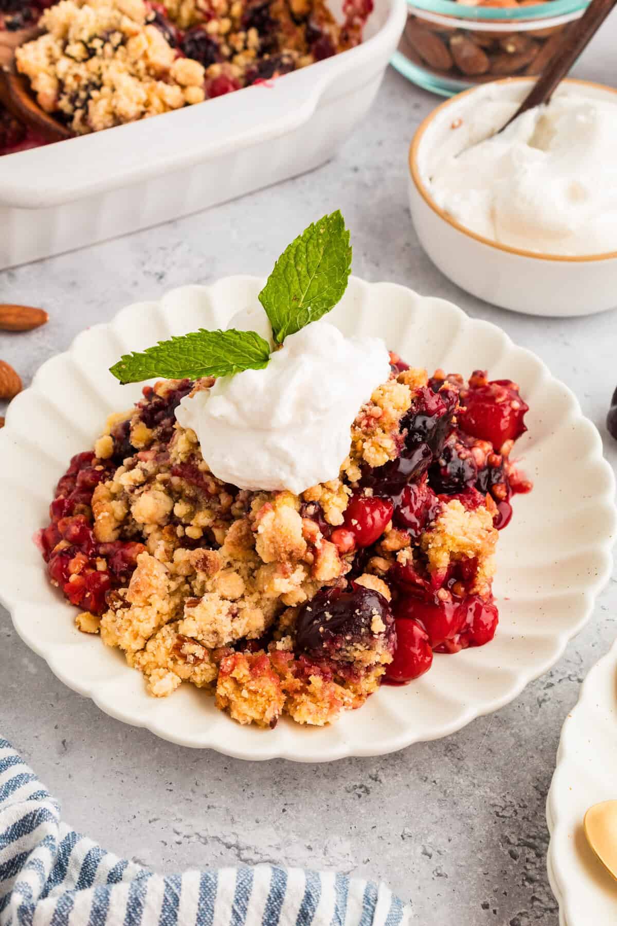 Cherry cobbler with cake mix topped with whipped cream and mint.