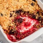 Cherry cobbler with cake mix in a white baking dish, showing a golden crumbly topping and a cherry filling.