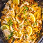 Slow cooker chicken shawarma, featuring marinated shredded chicken, onions, lemon wedges, and garnished with chopped parsley.