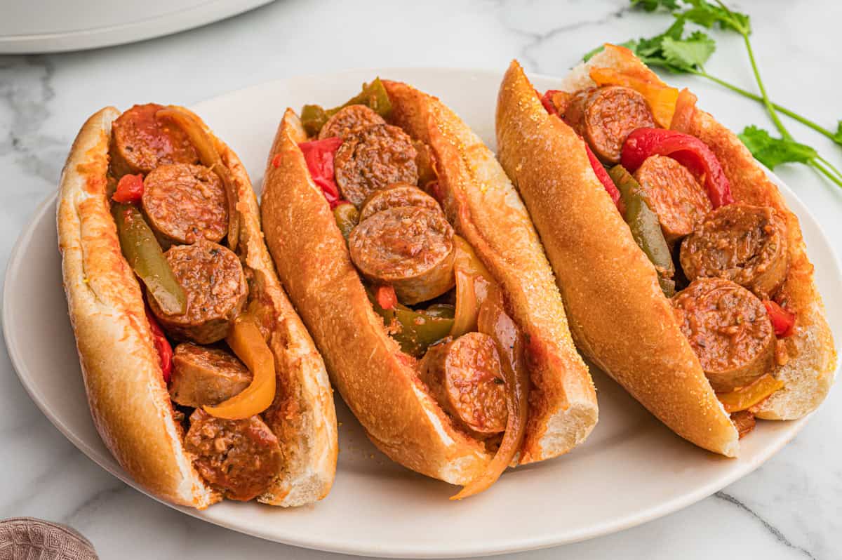 Three hoagie rolls filled with sausage, peppers, and onions.