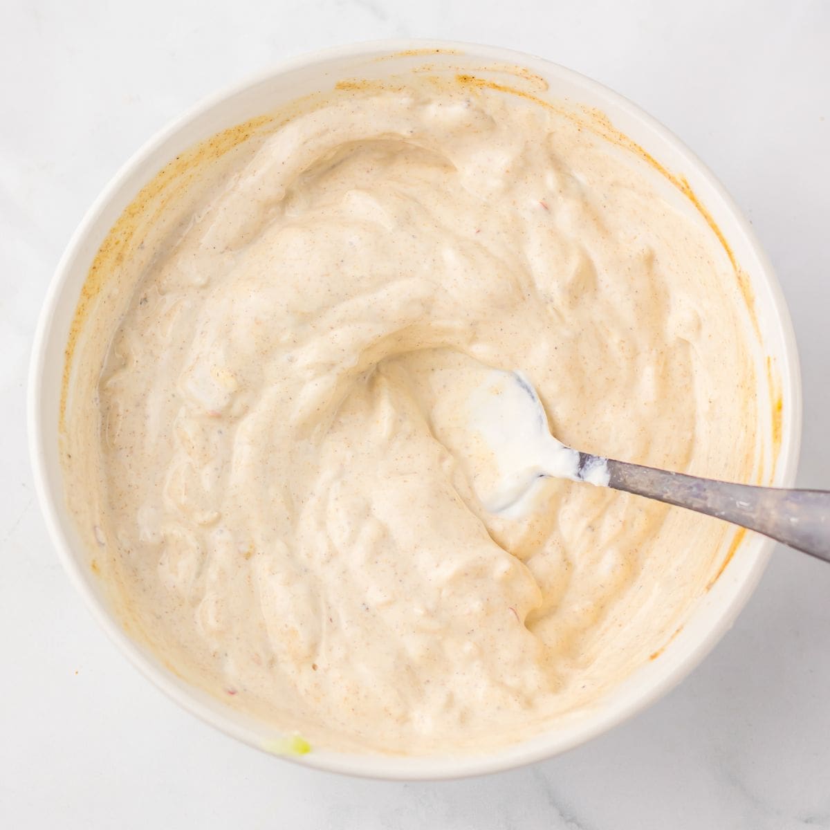 Bowl of creamy yogurt sauce with a spoon.