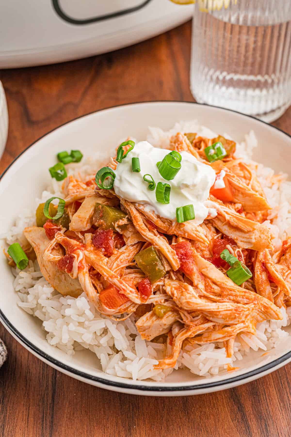 Bowl of rice topped with slow cooker chicken paprika, sour cream, and green onions.