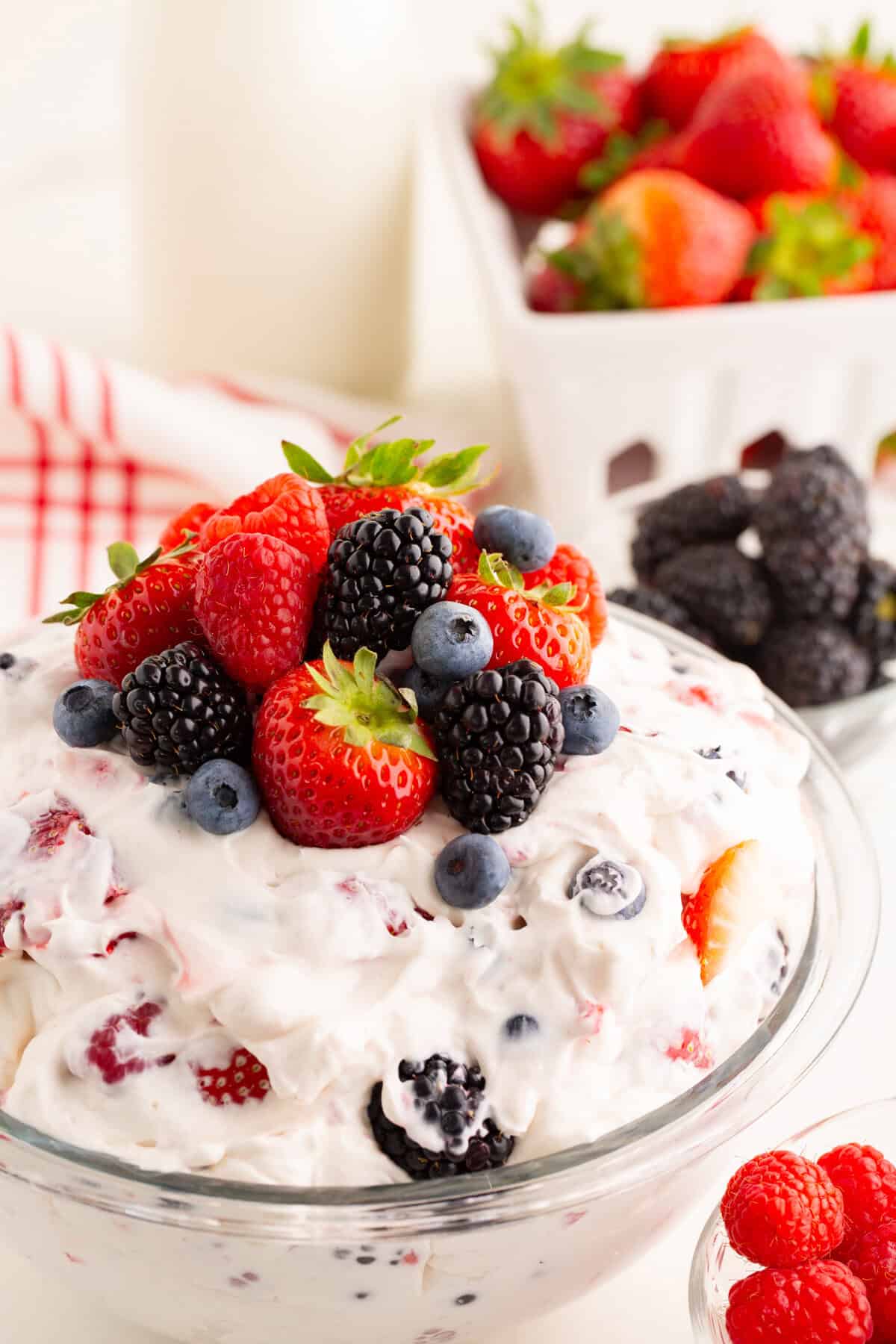 Close-up of a creamy berry cheesecake salad in a glass bowl, topped with strawberries, raspberries, blueberries, and blackberries.