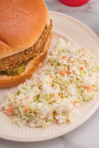 Close-up of finely chopped cabbage and carrot coleslaw with creamy dressing in a clear bowl.