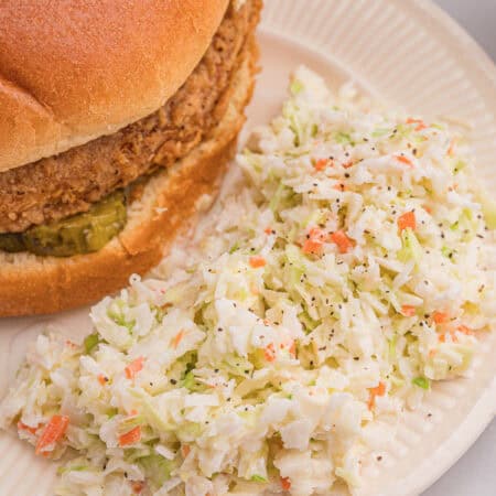 Close-up of finely chopped cabbage and carrot coleslaw with creamy dressing in a clear bowl.