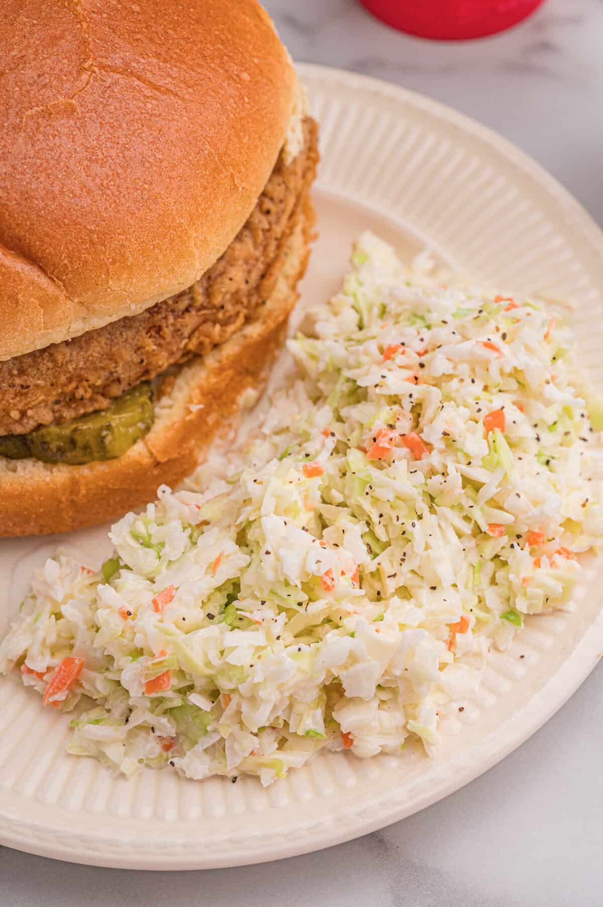 Close-up of finely chopped cabbage and carrot coleslaw with creamy dressing in a clear bowl.