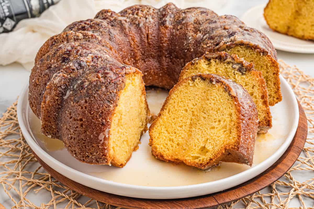 Glazed rum bundt cake on a white plate with slices cut showing the golden crumb.