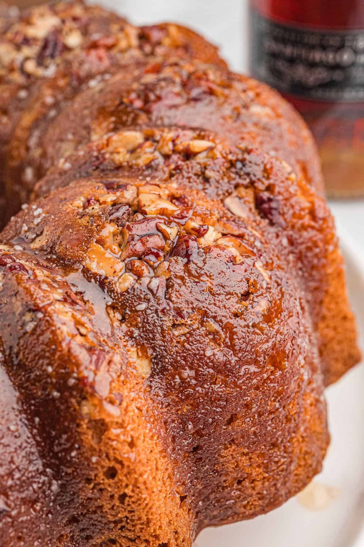 Close-up of a rum bundt cake with glossy glaze and chopped pecans on top.