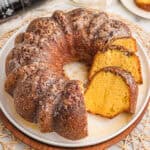 Rum cake recipe with cake mix sliced on a white plate with glaze and chopped pecans on top.