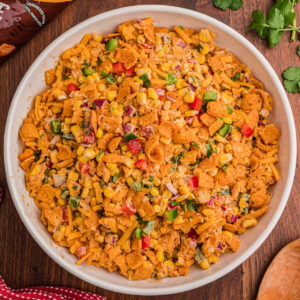 Overhead view of corn salad with Fritos in a white bowl topped with crushed Chili Cheese Fritos and diced bell pepper.