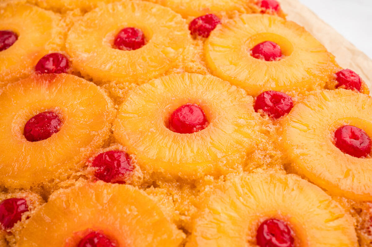 Overhead view of finished pineapple upside down cake with rows of cherry-centered pineapple rings in a brown sugar glaze.