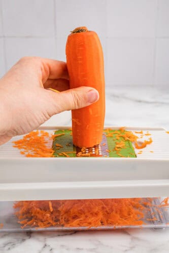 Carrot being shred with veggie chopper / grater.