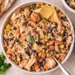 Overhead bowl of southwest chicken salad with black beans, corn, peppers, and a tortilla chip.