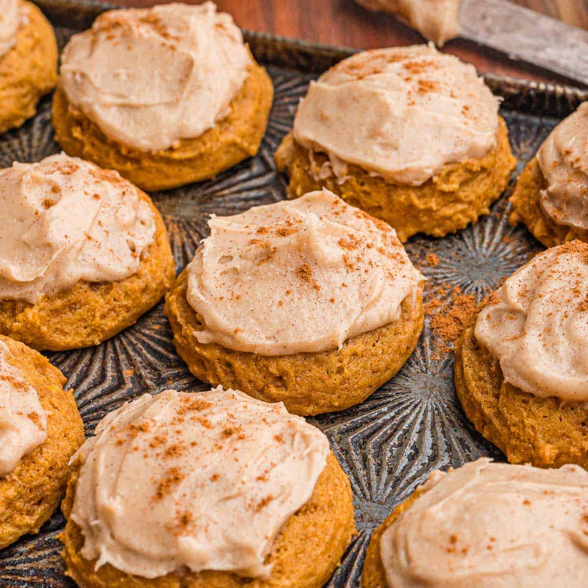 Frosted pumpkin cookies dusted with cinnamon.