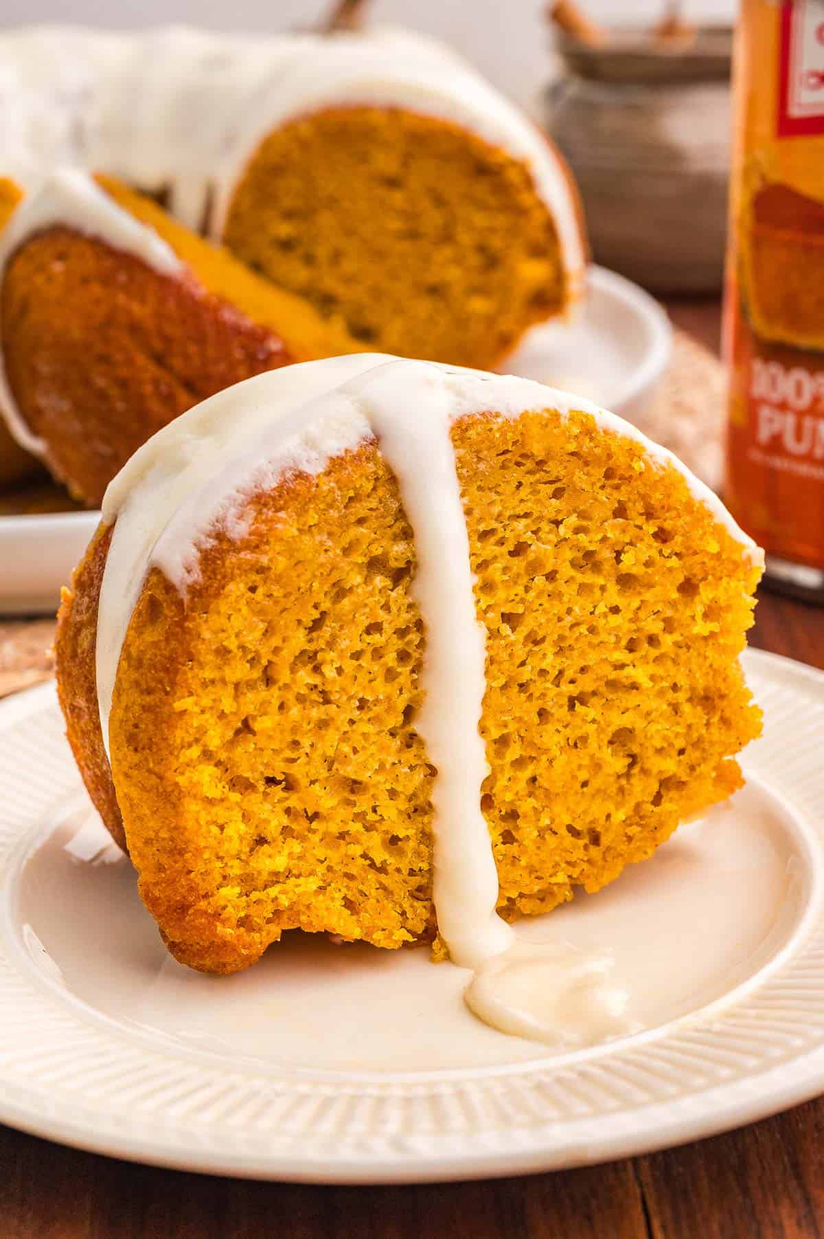 Sliced pumpkin bundt cake on a white plate with glaze, cut slices fanned out to the left.