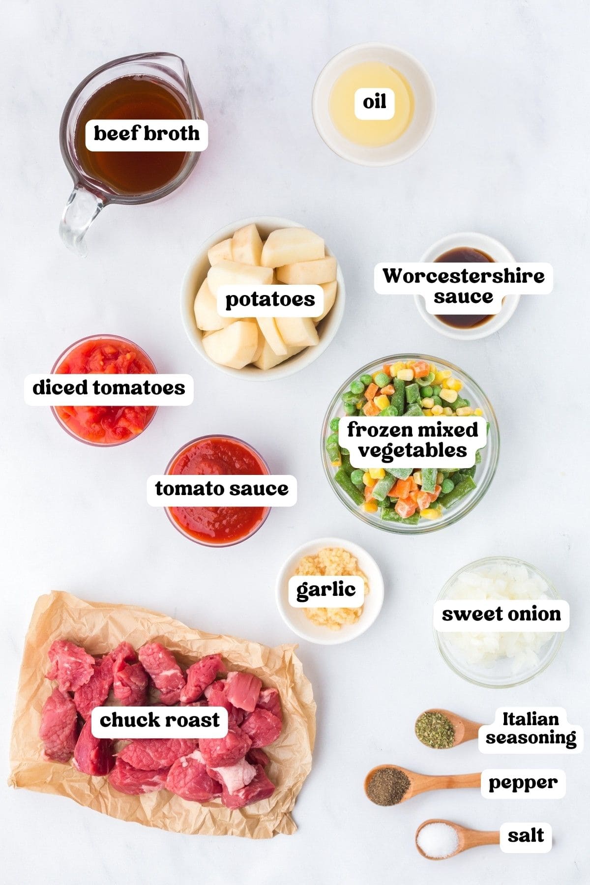 Labeled ingredients on white: beef broth, oil, potatoes, Worcestershire sauce, diced tomatoes, tomato sauce, frozen mixed vegetables, garlic, sweet onion, chuck roast, and seasonings.
